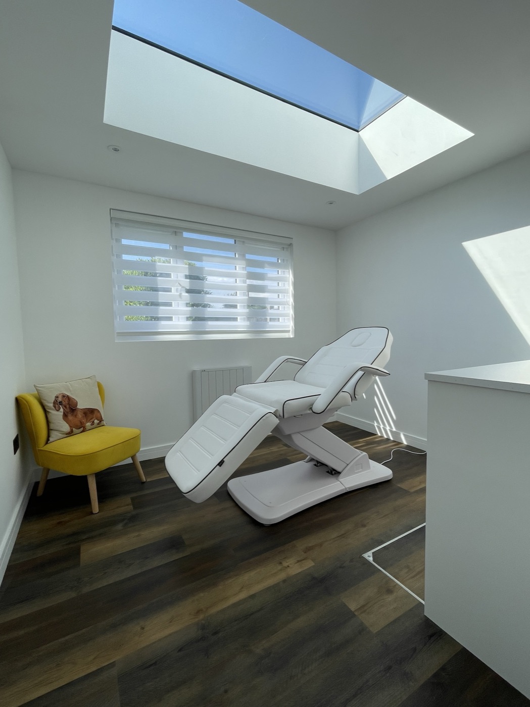Bright treatment room with skylight, treatment bed and yellow armchair